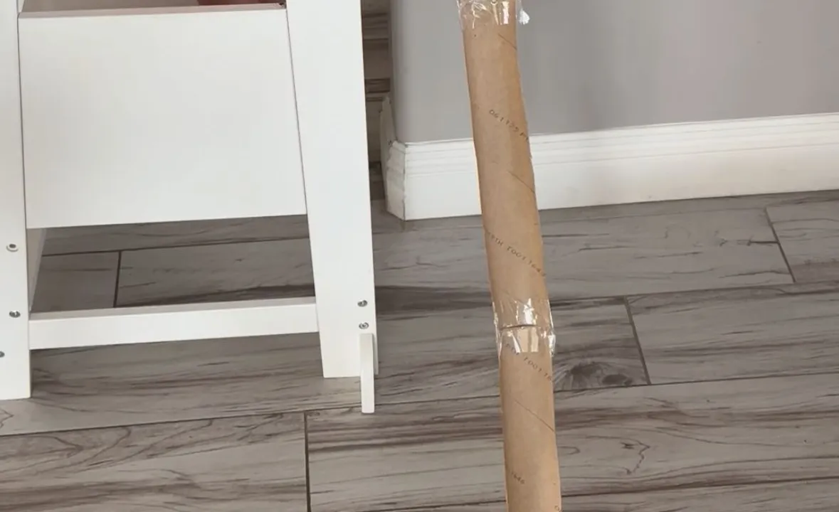 Toddler releasing a small toy car down a paper towel roll taped to a wall as a ramp