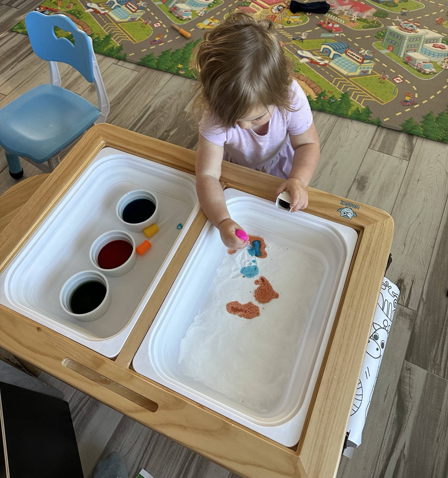 A toddler playing independently with an Independent Play Playbook activity while a parent works nearby