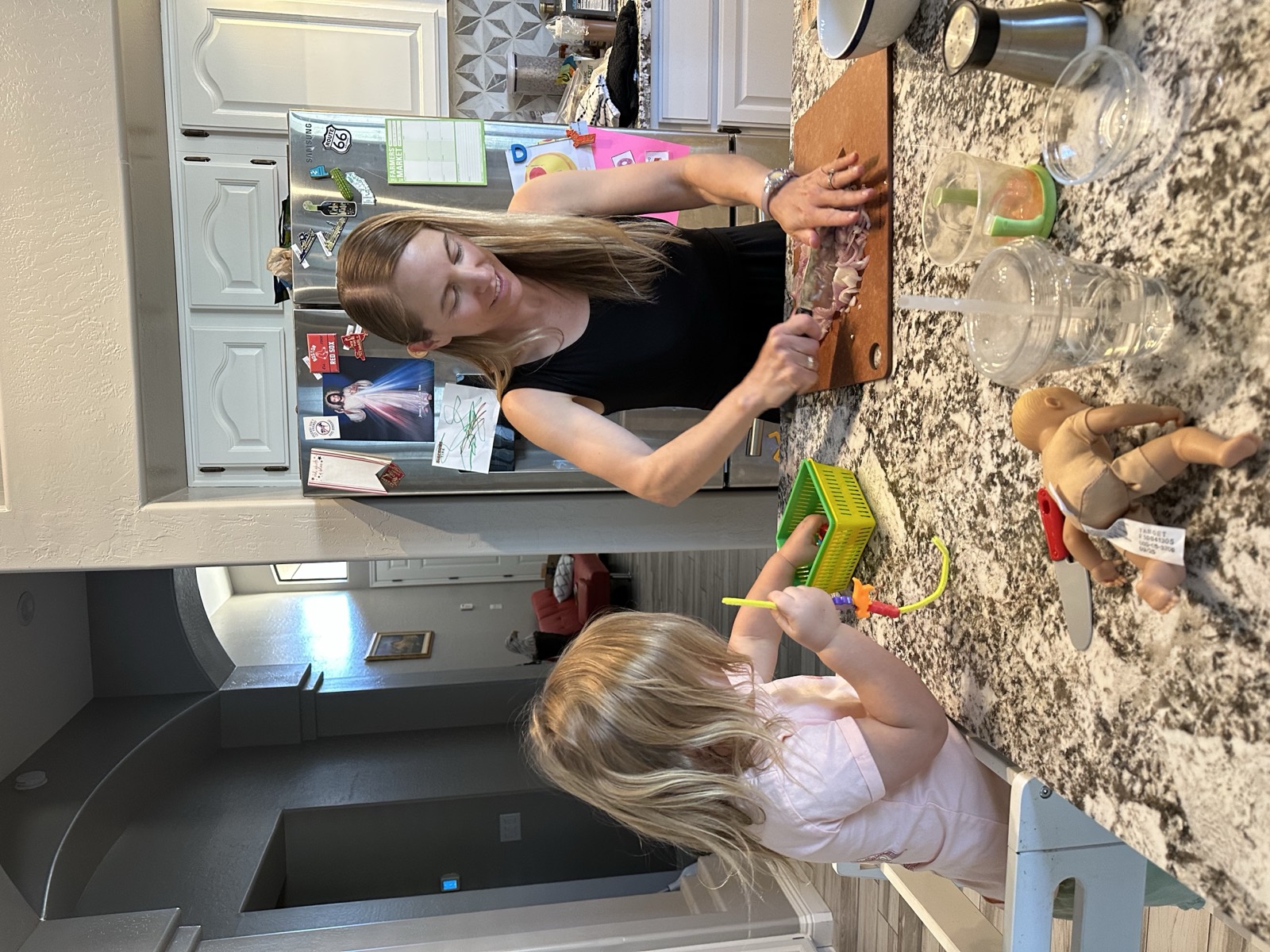 A toddler calmly engaged in a Meltdown Playbook activity at the kitchen table during the dinner hour